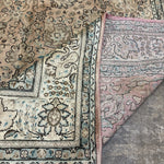 Tabriz-style rug corner detail with teal-blue border lines and patterned cream field.