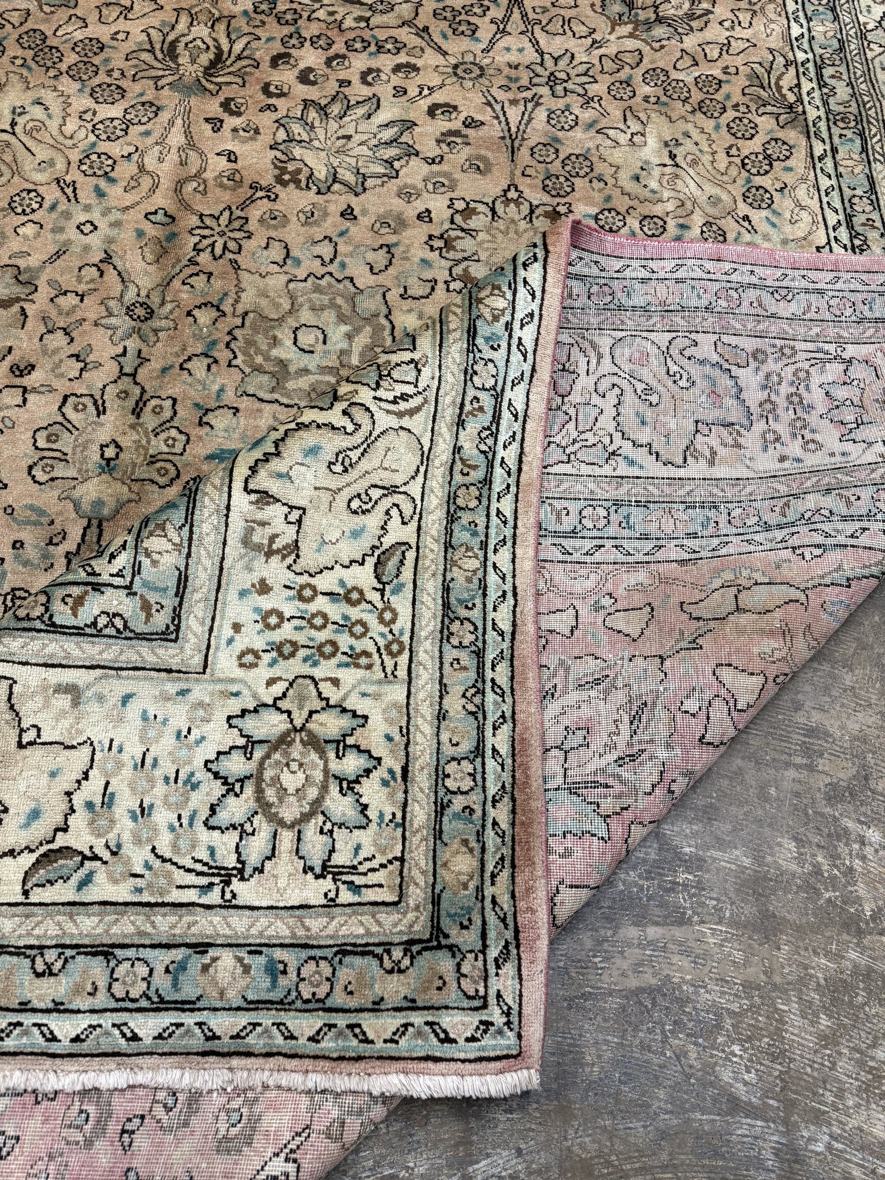 Tabriz-style rug corner detail with teal-blue border lines and patterned cream field.