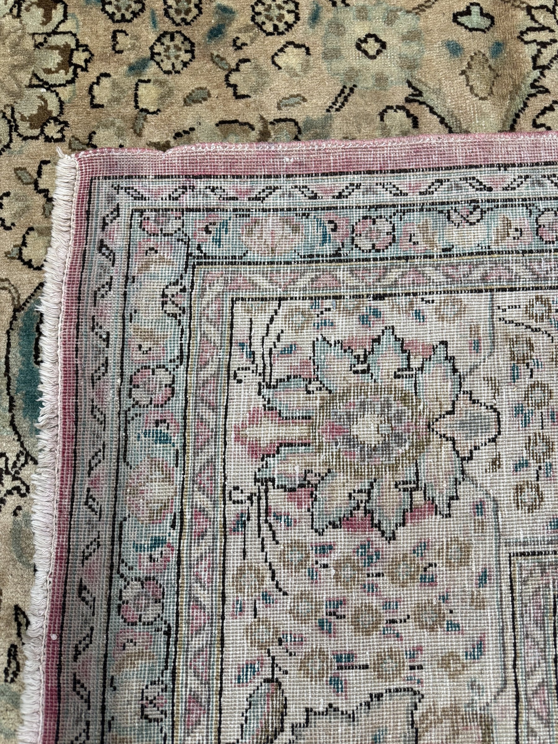 Tabriz-style rug border close-up with pink edge trim and floral medallion details.
