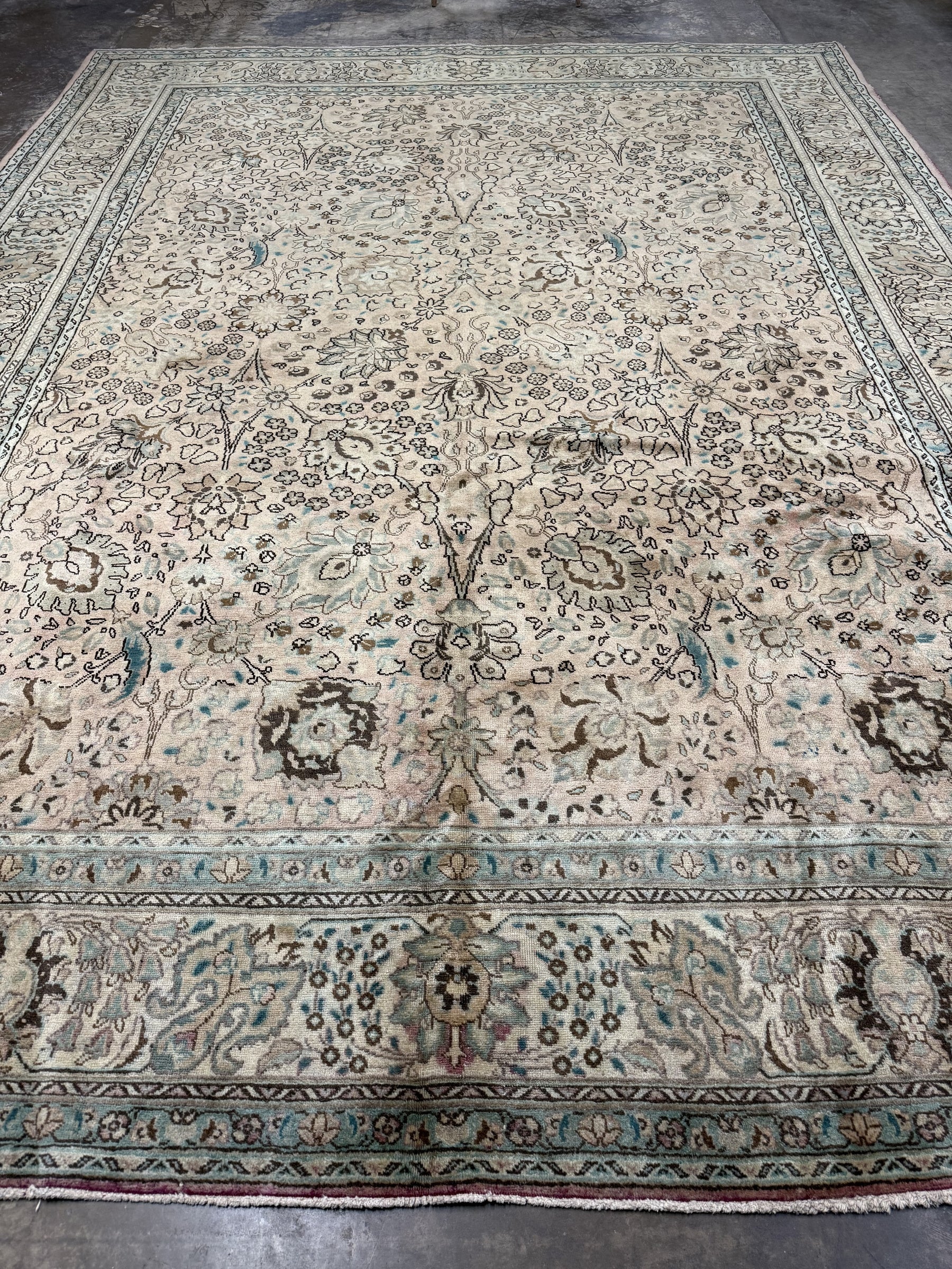 Tabriz-style rug, cream tone with teal-blue border stripes and ornate floral layout.