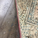 Rug edge detail with cream field, teal outlines, and red binding along the side