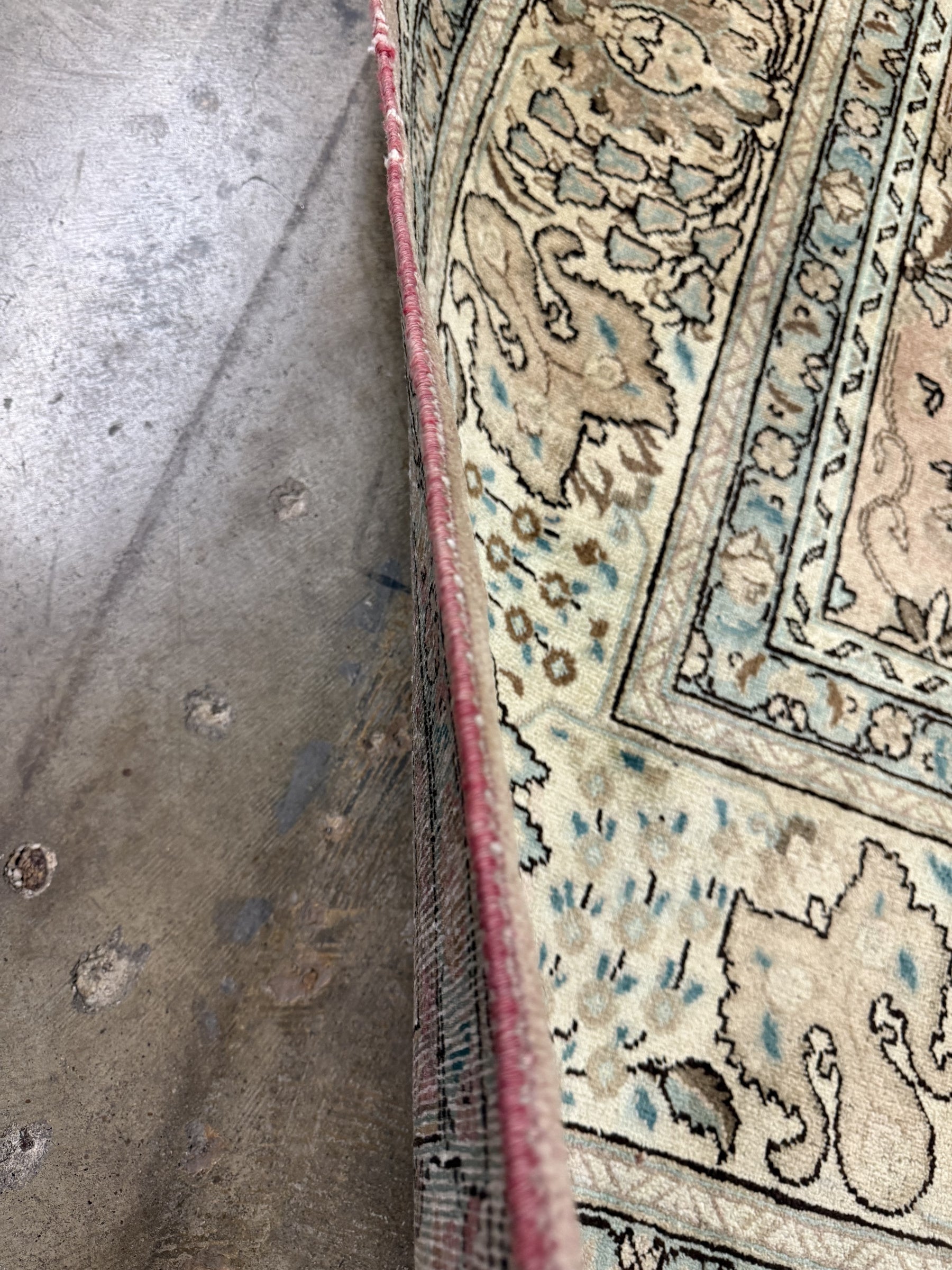 Rug edge detail with cream field, teal outlines, and red binding along the side