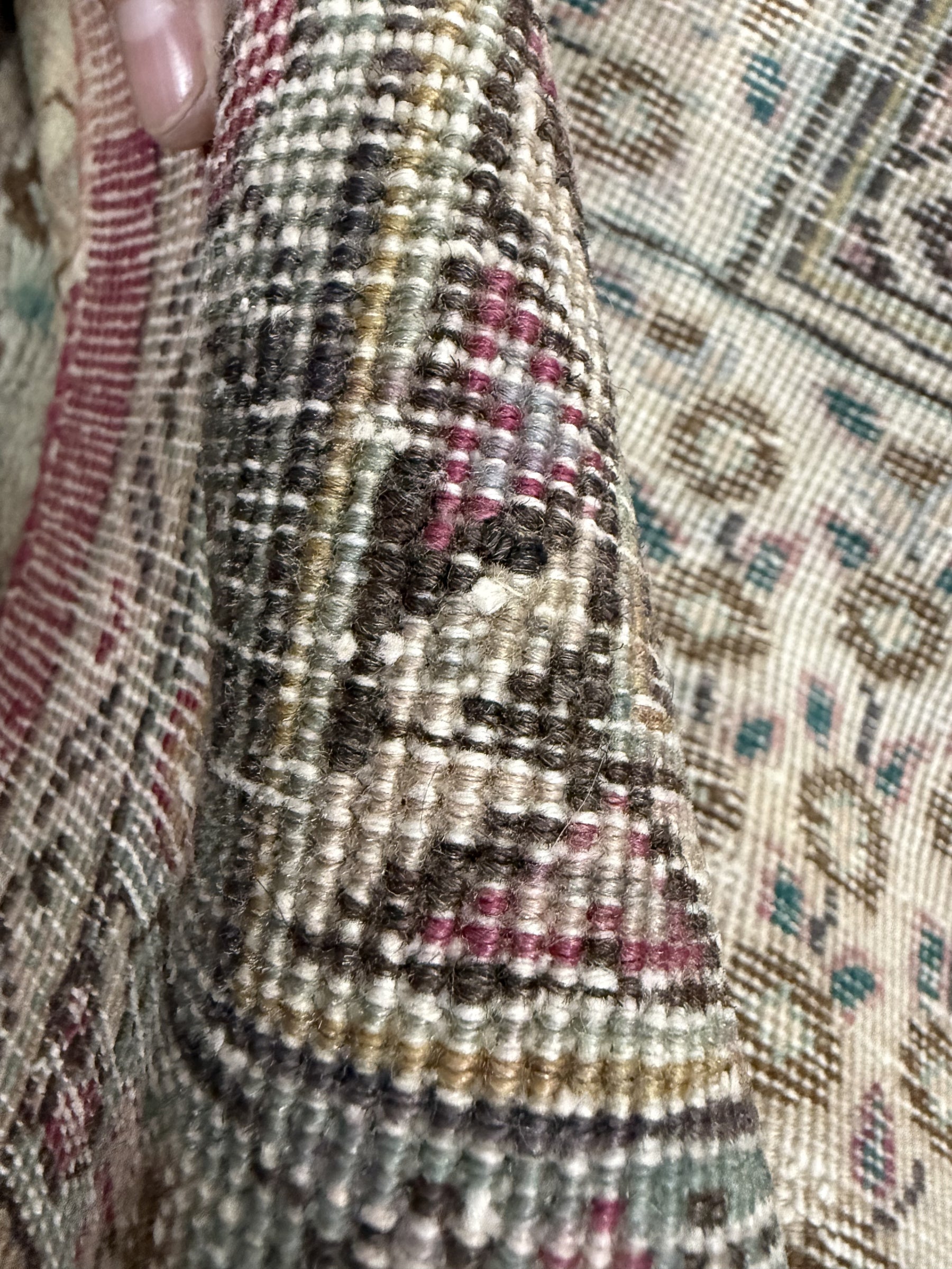 Close-up of rug fringe and textured weave with black, gold, and muted red accents