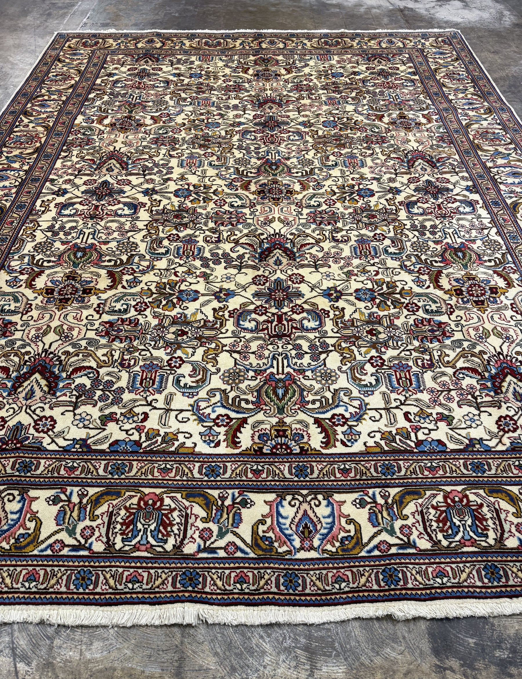 Tabriz-style rug, cream field with navy, red and blue floral medallions, wide border