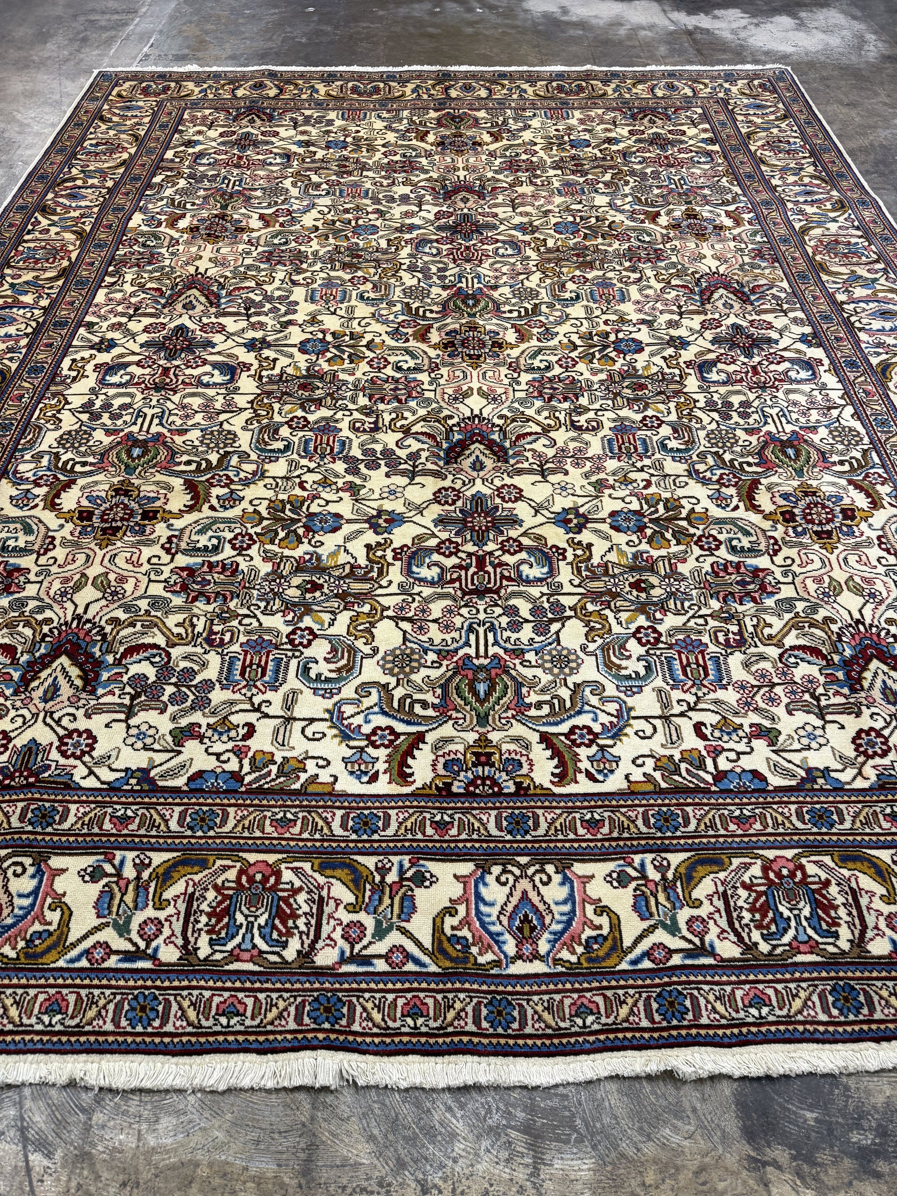 Tabriz-style rug, cream field with navy, red and blue floral medallions, wide border