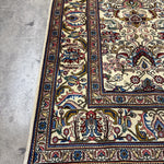 Tabriz rug border detail with rosette and scrolling motifs in red, blue, gold on cream