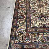 Tabriz rug border detail with rosette and scrolling motifs in red, blue, gold on cream