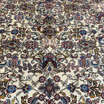 Tabriz rug close-up: cream background with red, blue, green floral scrollwork