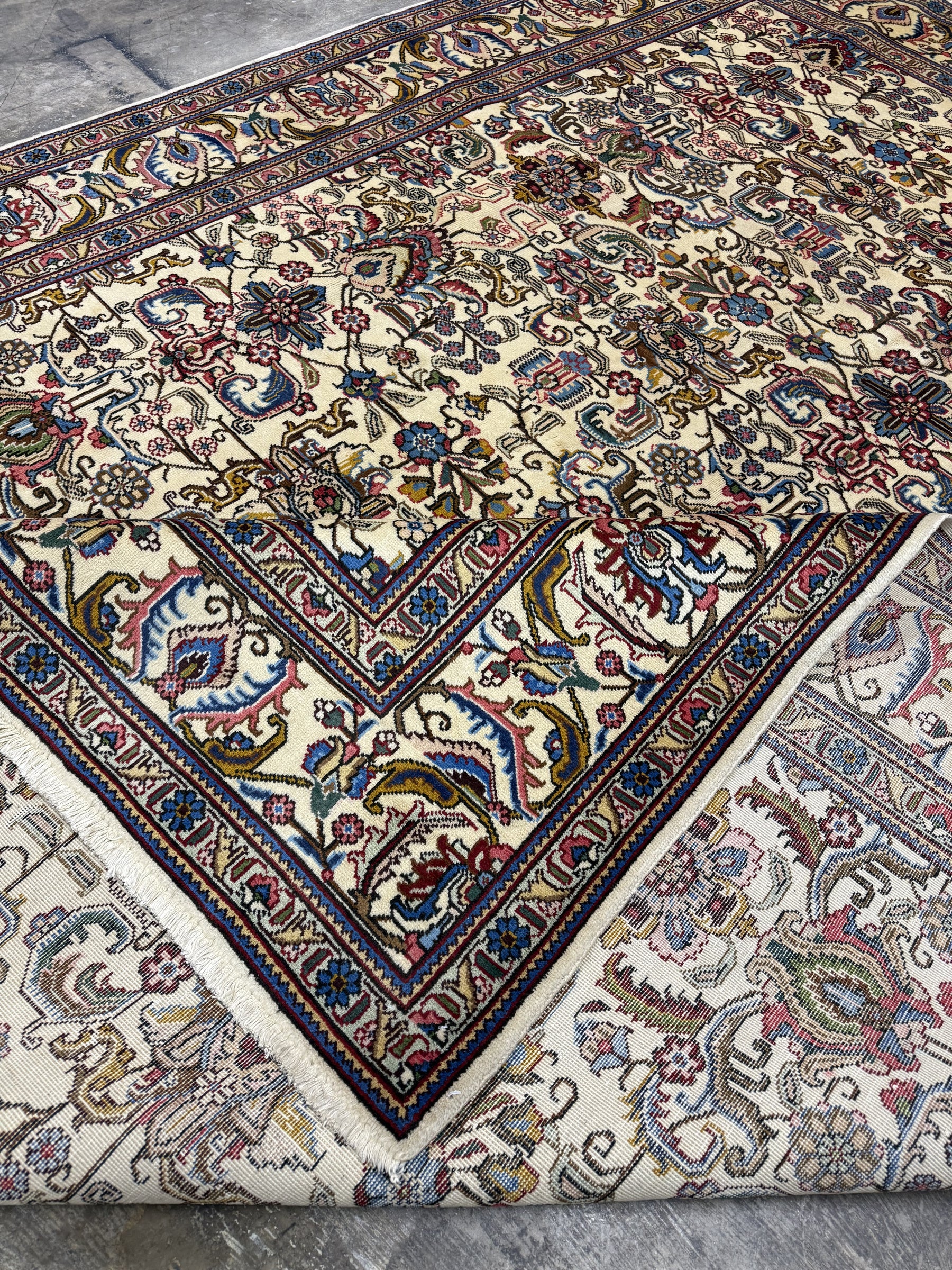 Tabriz rug folded corner showing ornate vase and floral pattern, multicolor border, fringe