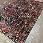 Bakhtiari Persian rug corner view with red and navy patterned panels and fringed edge