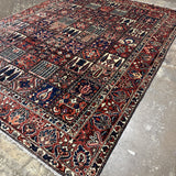 Bakhtiari Persian rug corner view with red and navy patterned panels and fringed edge
