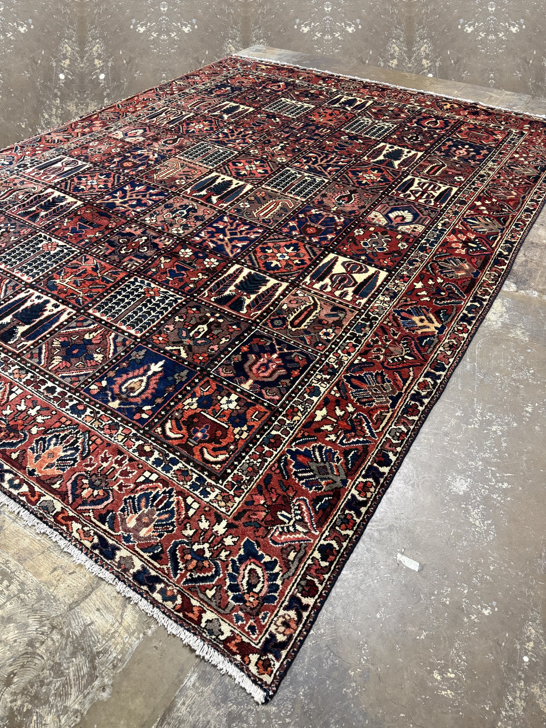 Bakhtiari Persian rug corner view with red and navy patterned panels and fringed edge