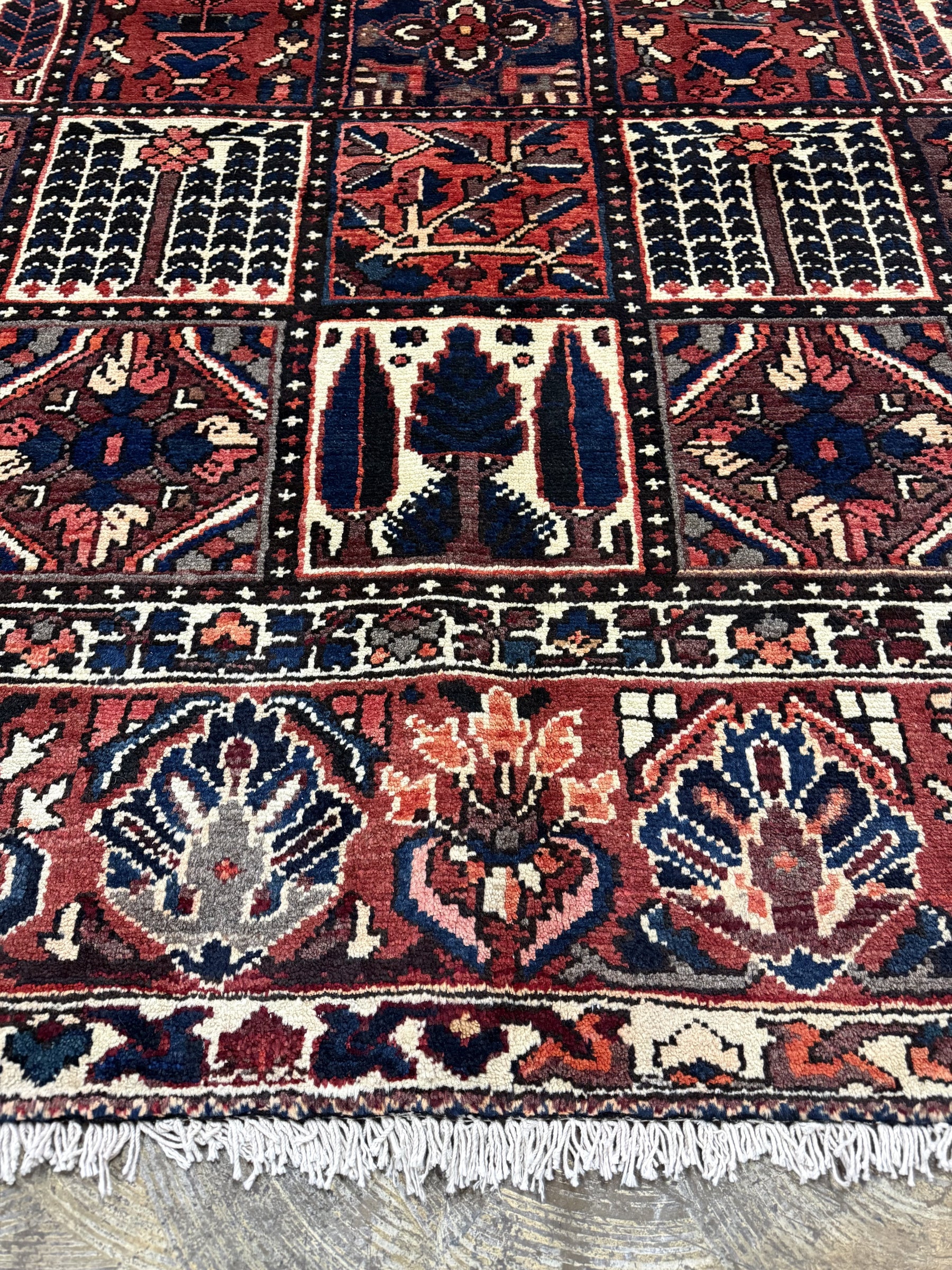 Bakhtiari Persian rug close-up with red and navy panels, cream accents, and fringe