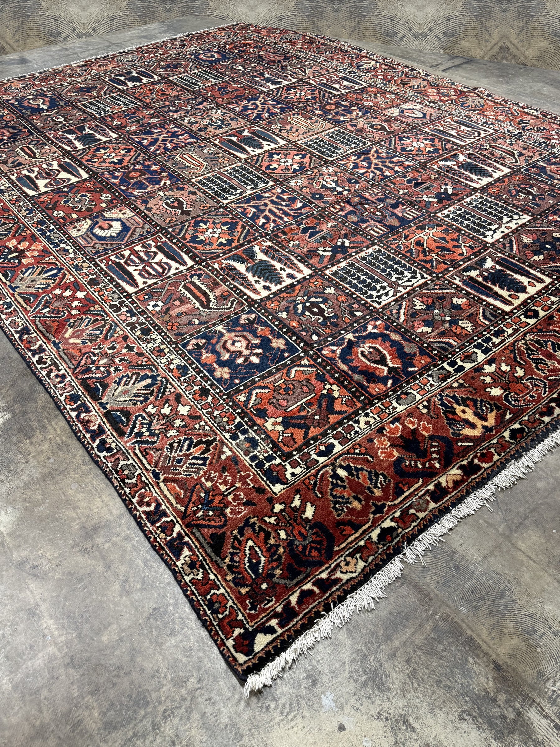 Persian-style rug with geometric medallion pattern, navy, rust, and cream, fringed ends