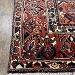 Geometric rug border in rust and navy with cream accents, short fringe along bottom