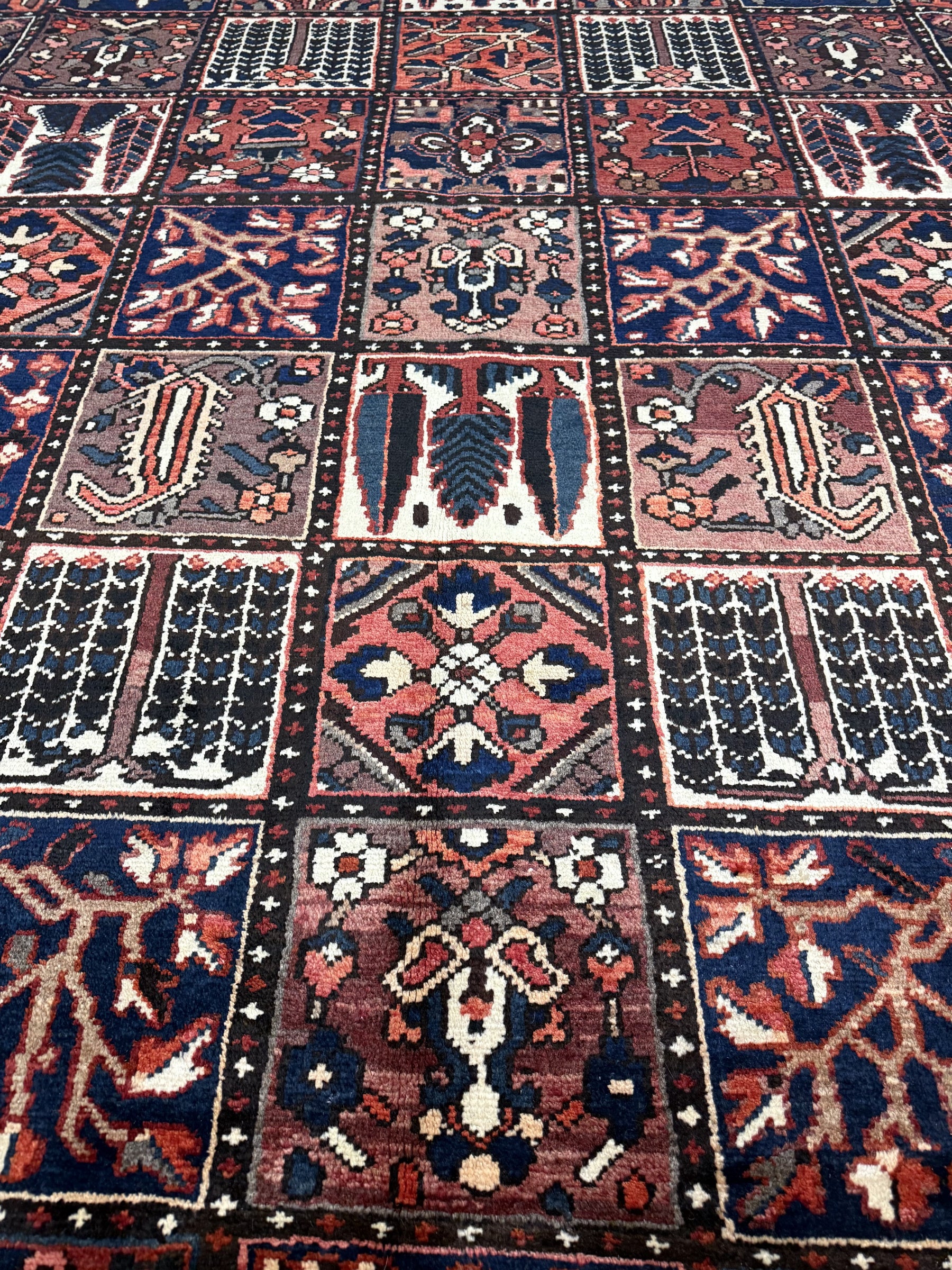 Geometric Persian rug panel design in navy, rust, and cream, closely detailed motifs