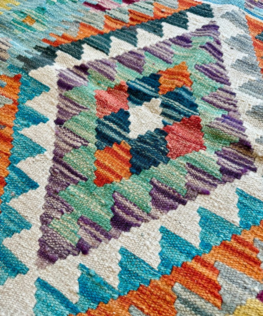 Close-up kilim runner rug with multicolor zigzag and diamond woven pattern.