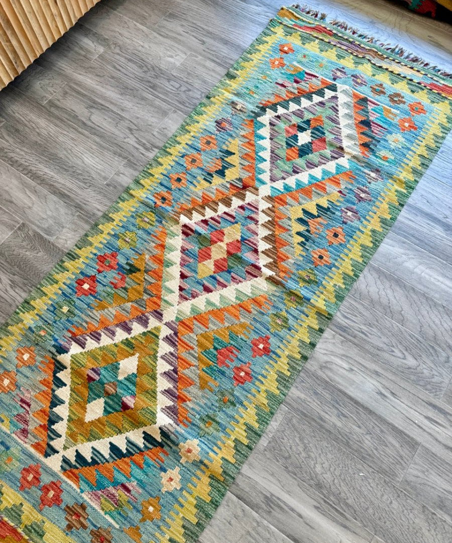 Woven kilim runner rug with colorful geometric medallion pattern and short fringed ends.