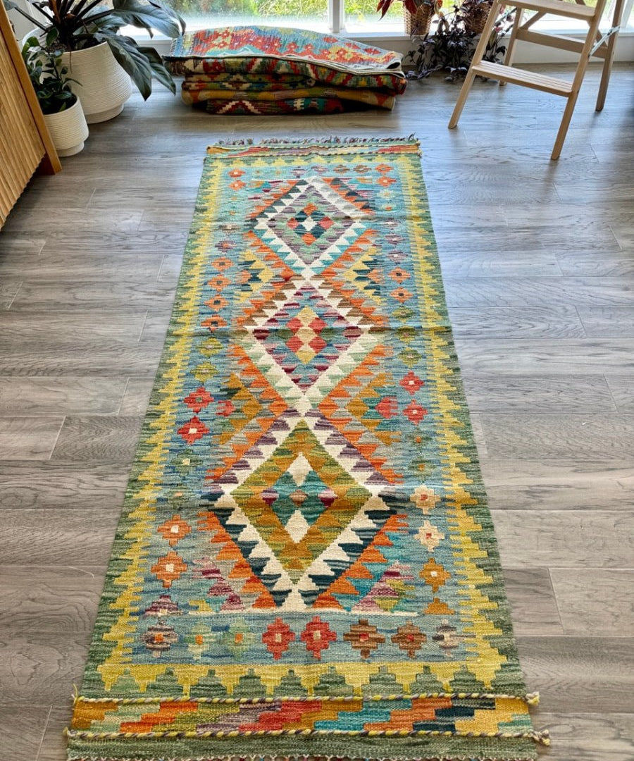 Kilim runner rug with multicolor diamond lattice center and fringed border.