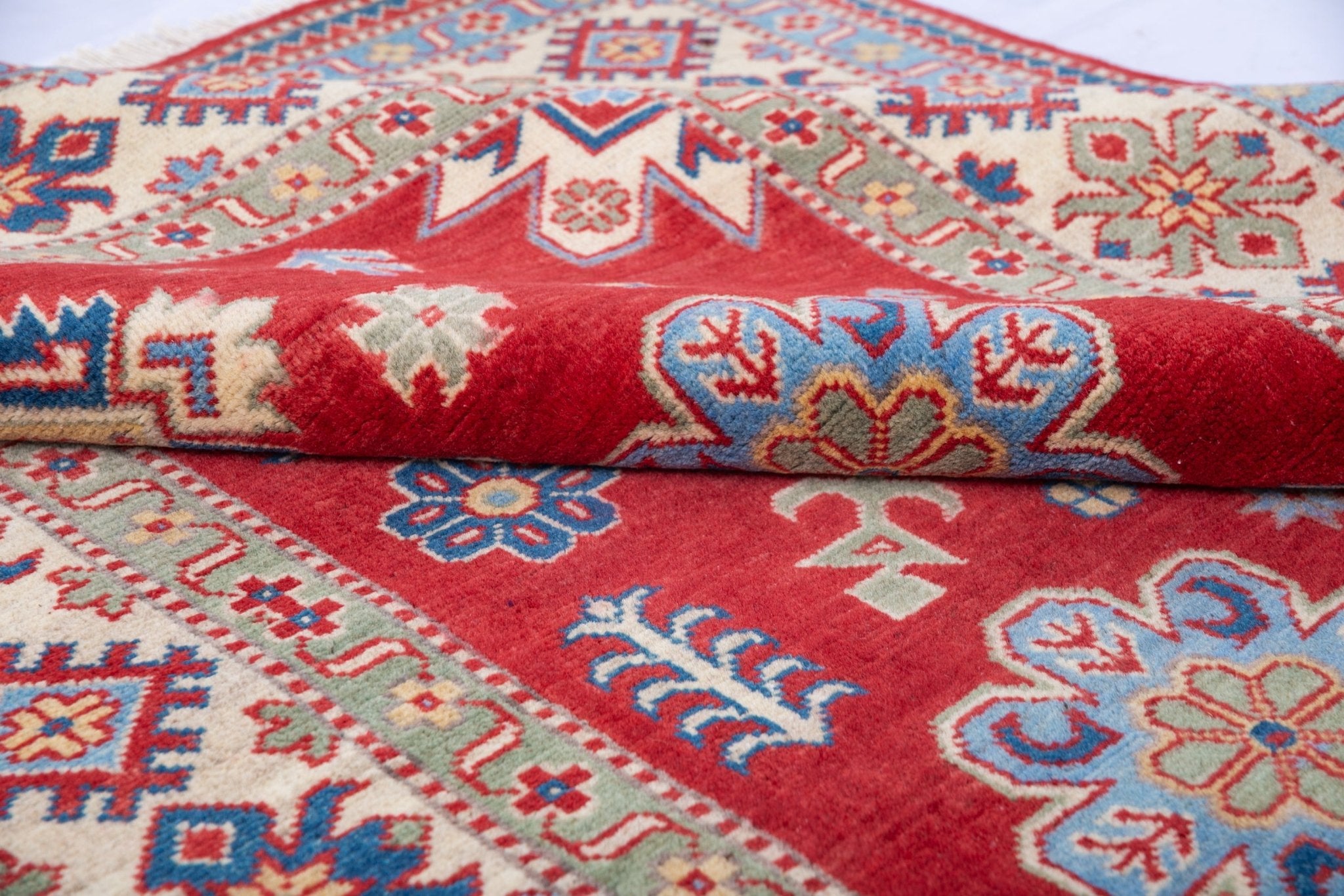 Folded edge and wool pile of red & ivory Kazak-inspired wool rug 21991.