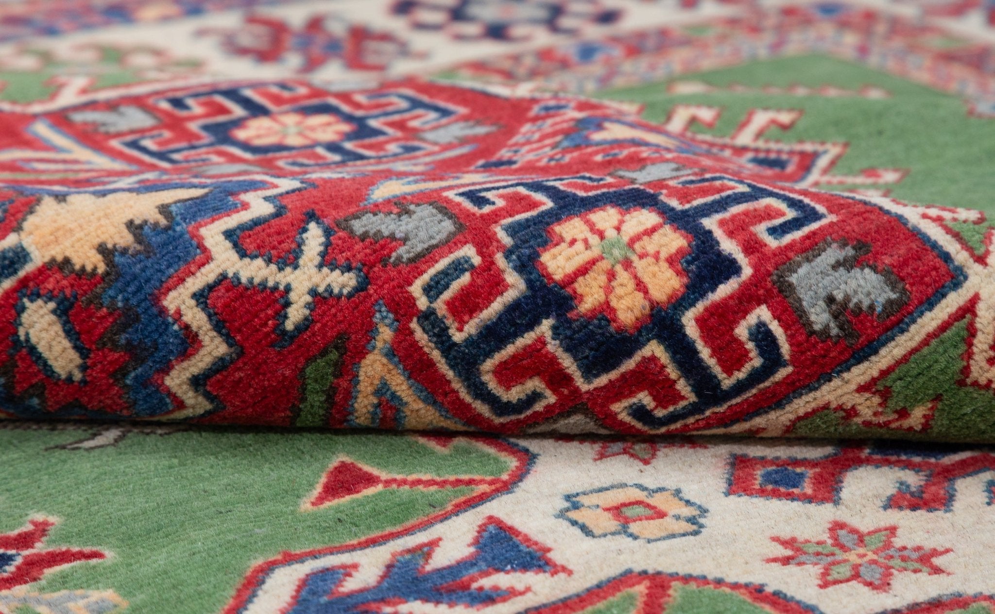 Folded edge and wool pile of green & red Kazak-inspired wool rug 29641.