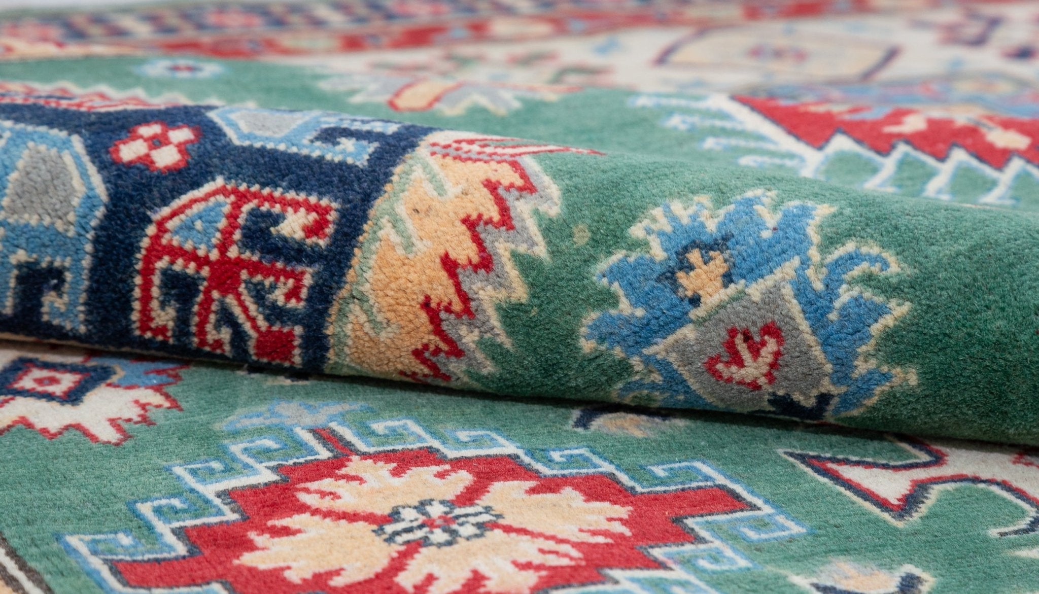 Folded edge and wool pile of green & ivory Kazak-inspired wool rug 29640.