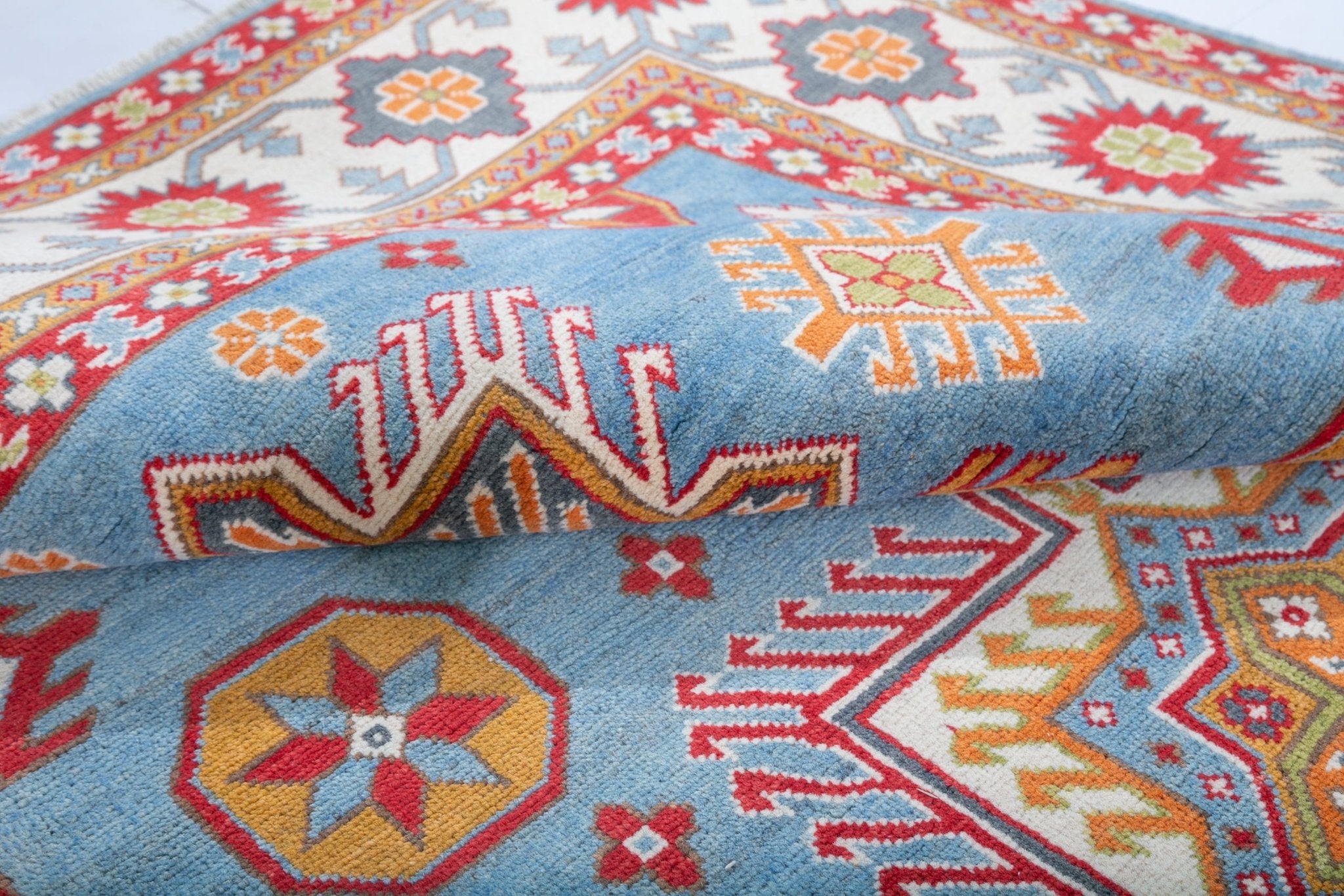 Folded edge and wool pile of blue & red Kazak-inspired wool rug 24986.