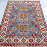 Full view from a low angle of blue & red Kazak-inspired wool rug 24986.