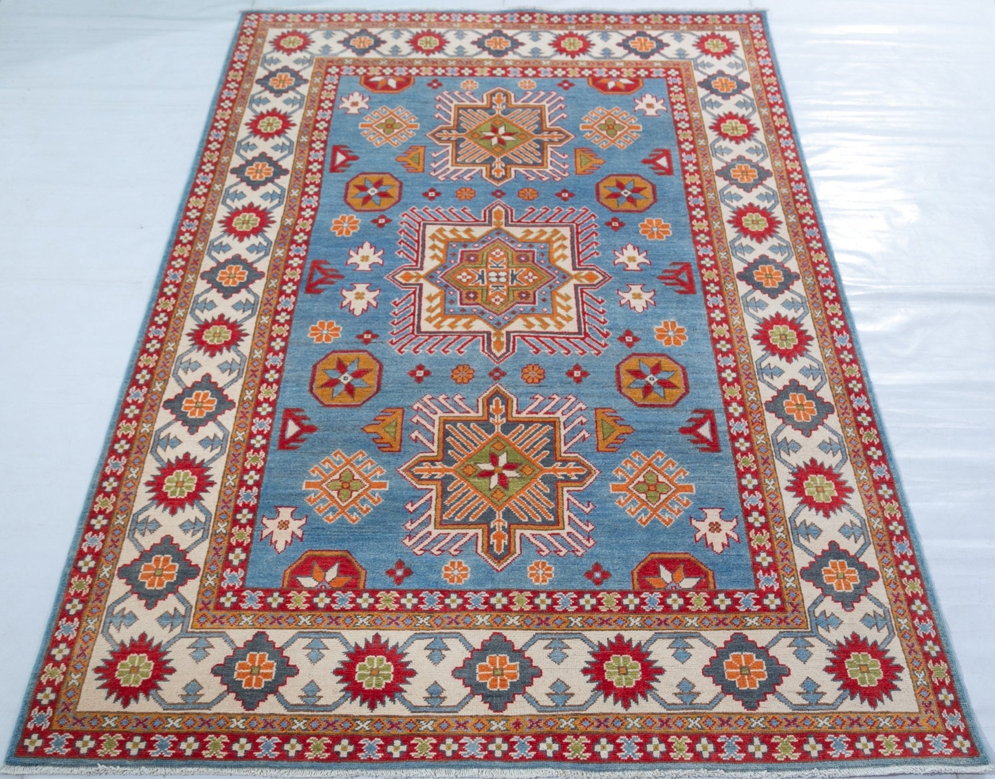 Full view from a low angle of blue & red Kazak-inspired wool rug 24986.