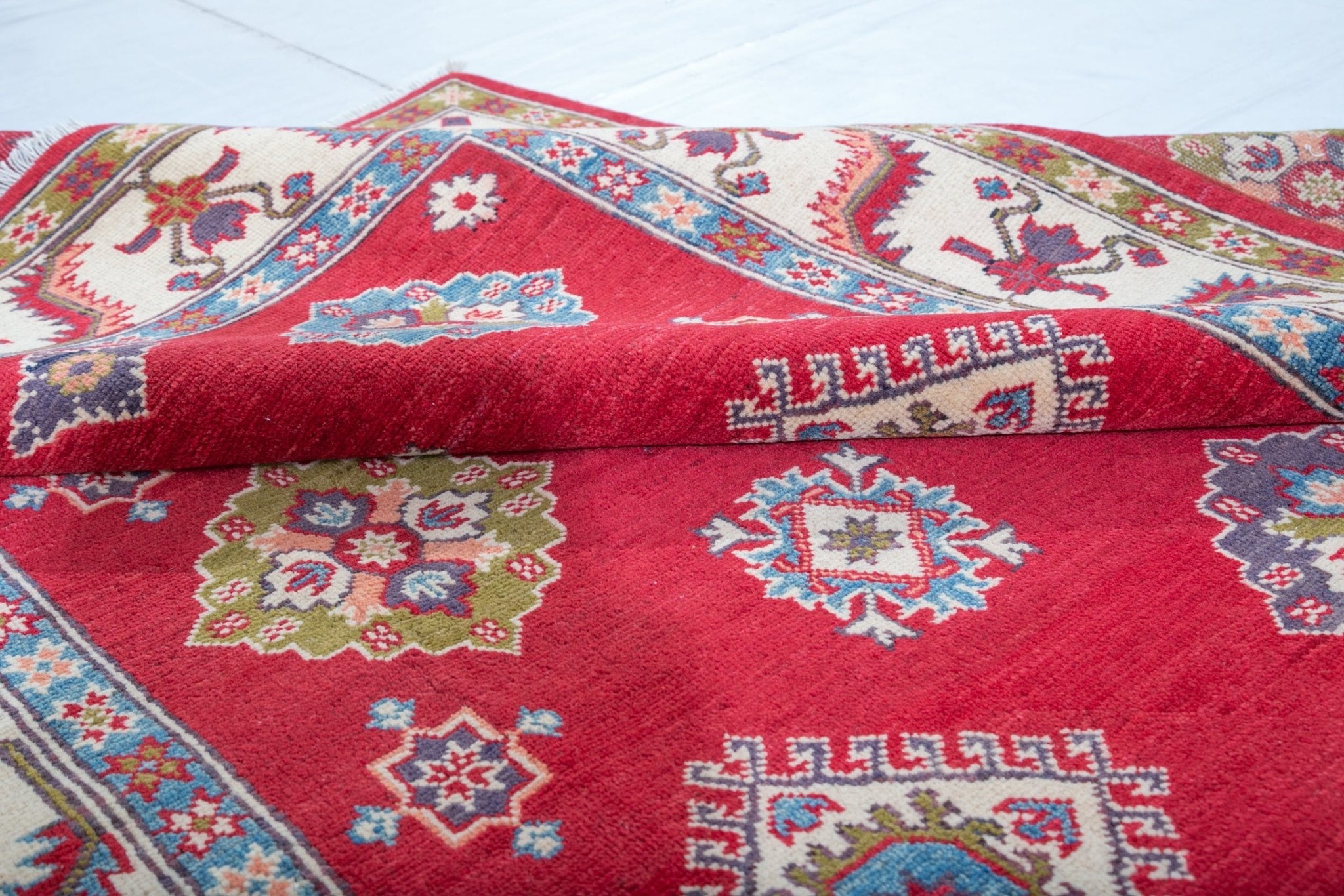 Folded edge and wool pile of red & blue Kazak-inspired wool rug 24995.