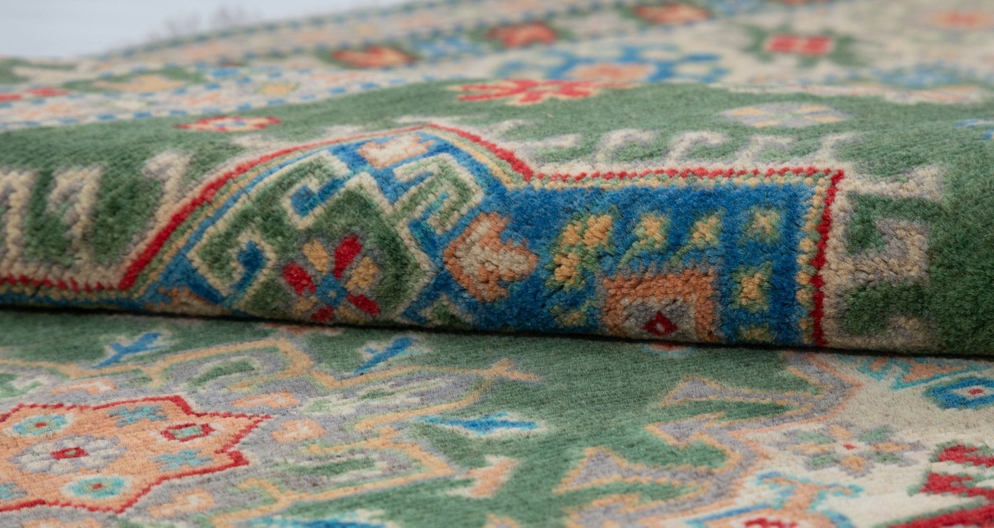 Folded edge and wool pile of green & blue Kazak-inspired wool rug 29637.