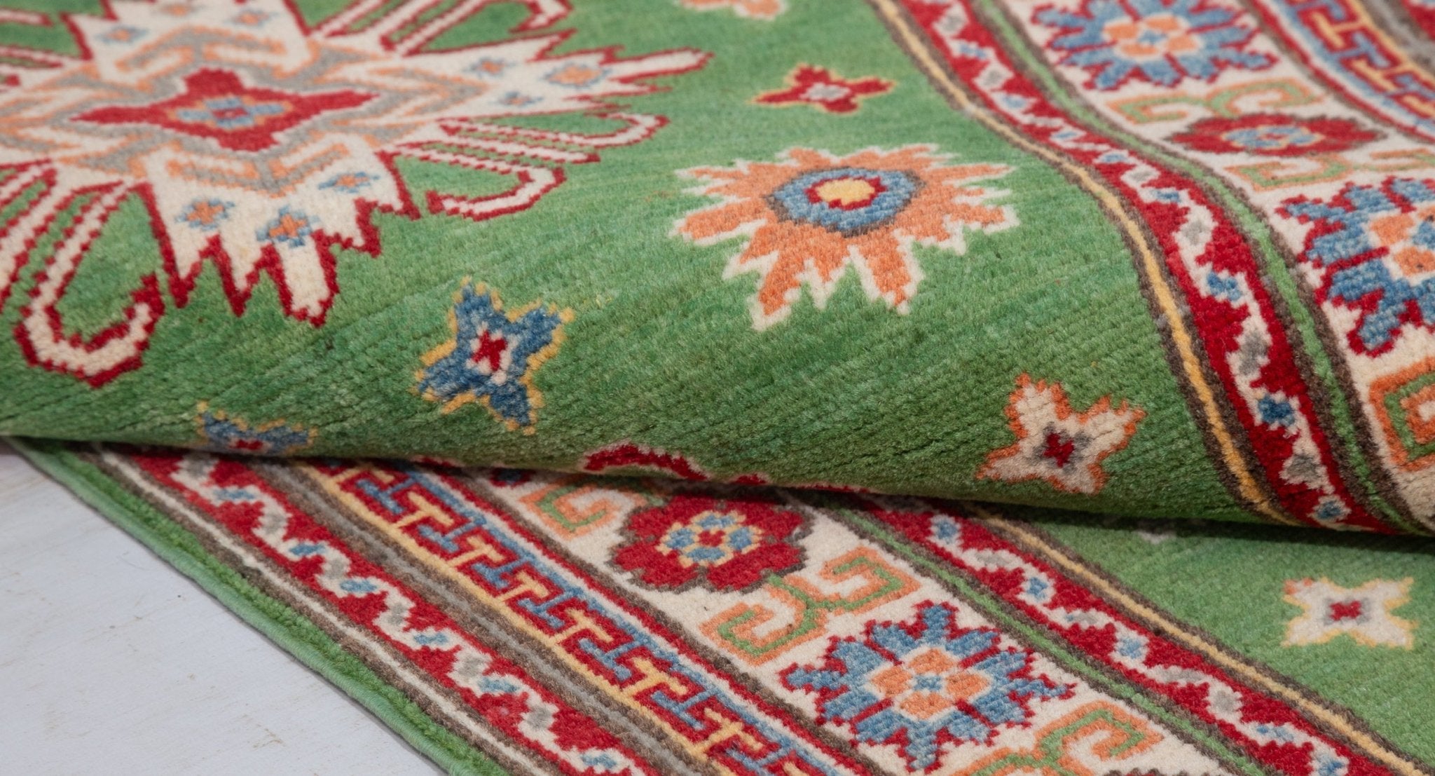 Folded edge and wool pile of green & red Kazak-inspired wool runner 29353.
