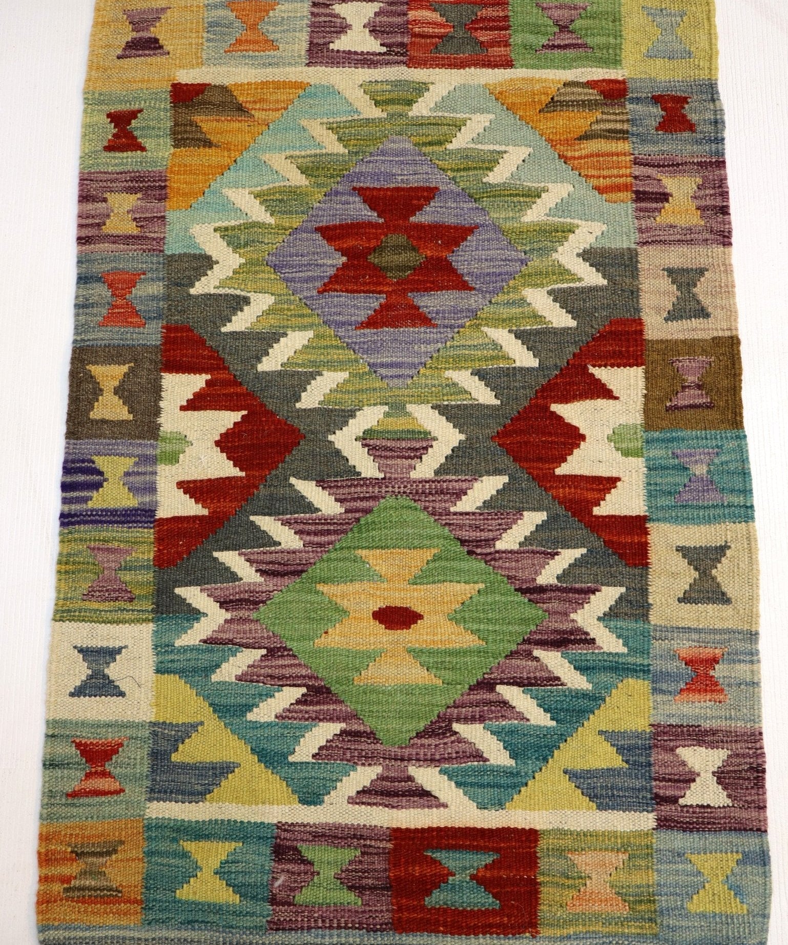 Afghan kilim rug with central diamond medallion, multicolor geometry, and fringe border