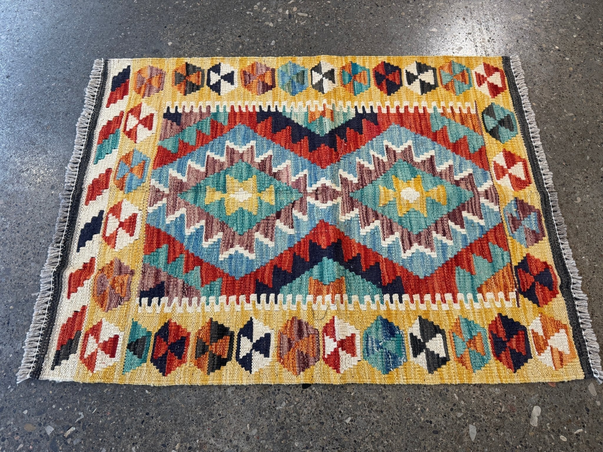 Kilim rug with turquoise and rust diamond pattern; cream field, multicolor border; fringe
