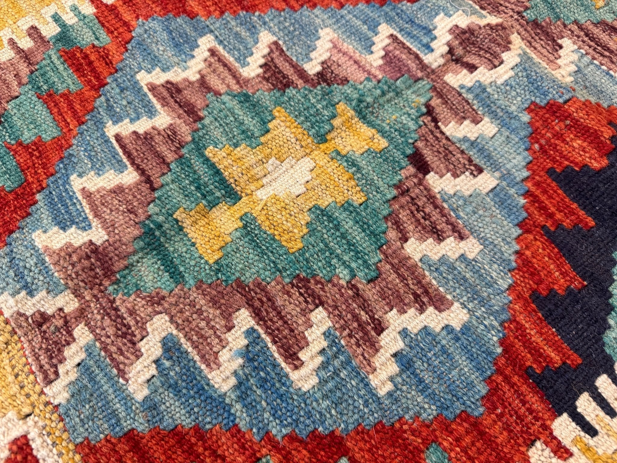 Kilim rug close-up: teal and blue diamonds with mustard and rust geometric blocks