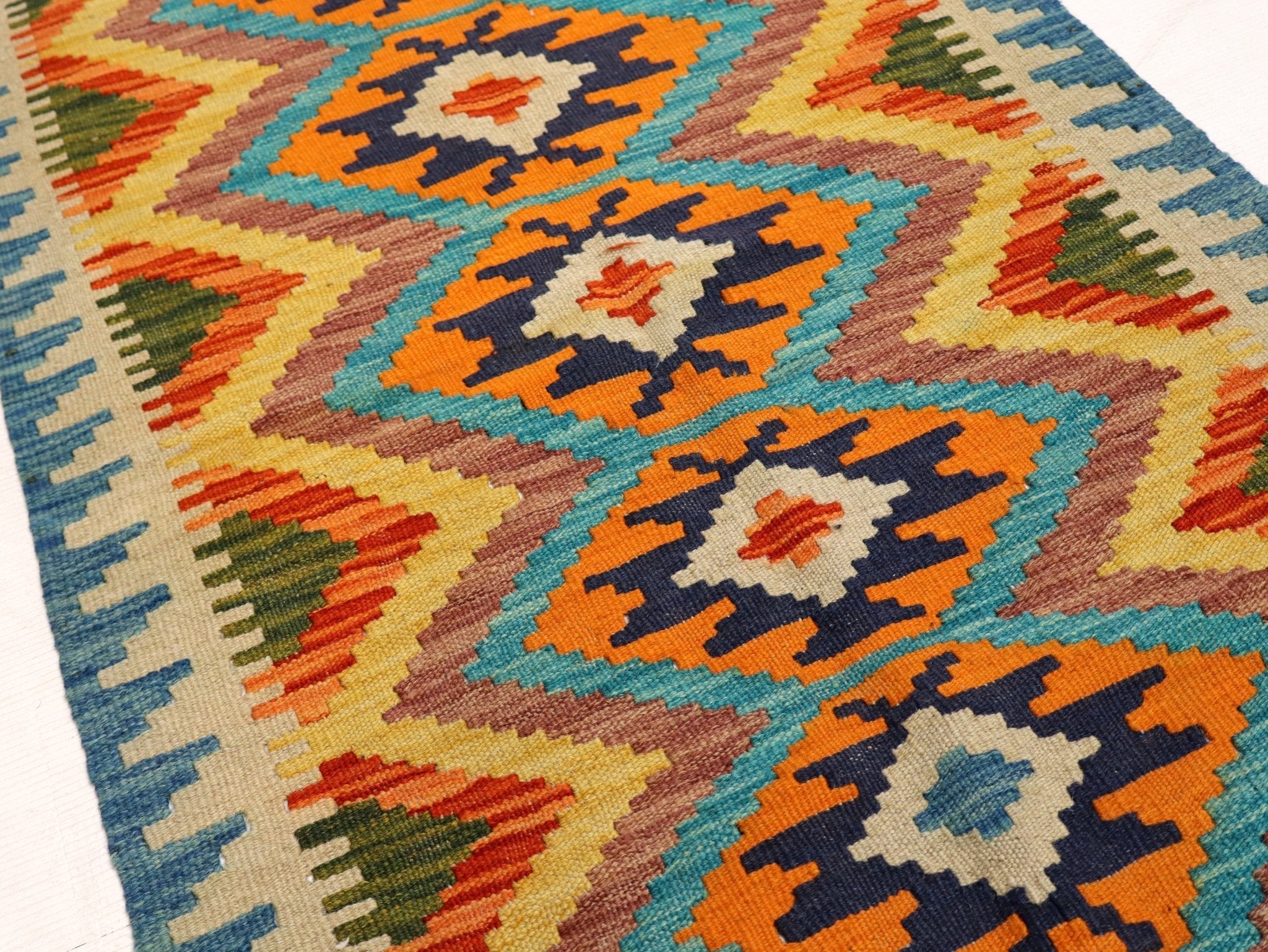 Kilim rug section with teal, orange and navy diamond medallion motifs