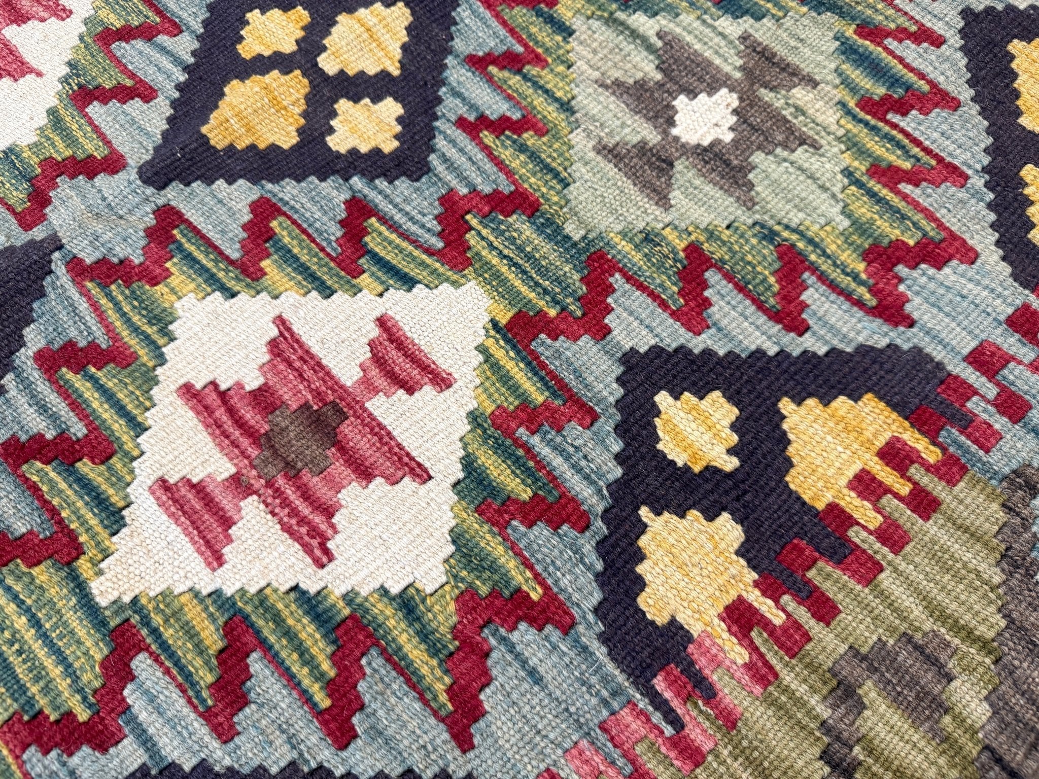 Close-up kilim rug section with white and cream shapes, yellow diamonds, navy outlines