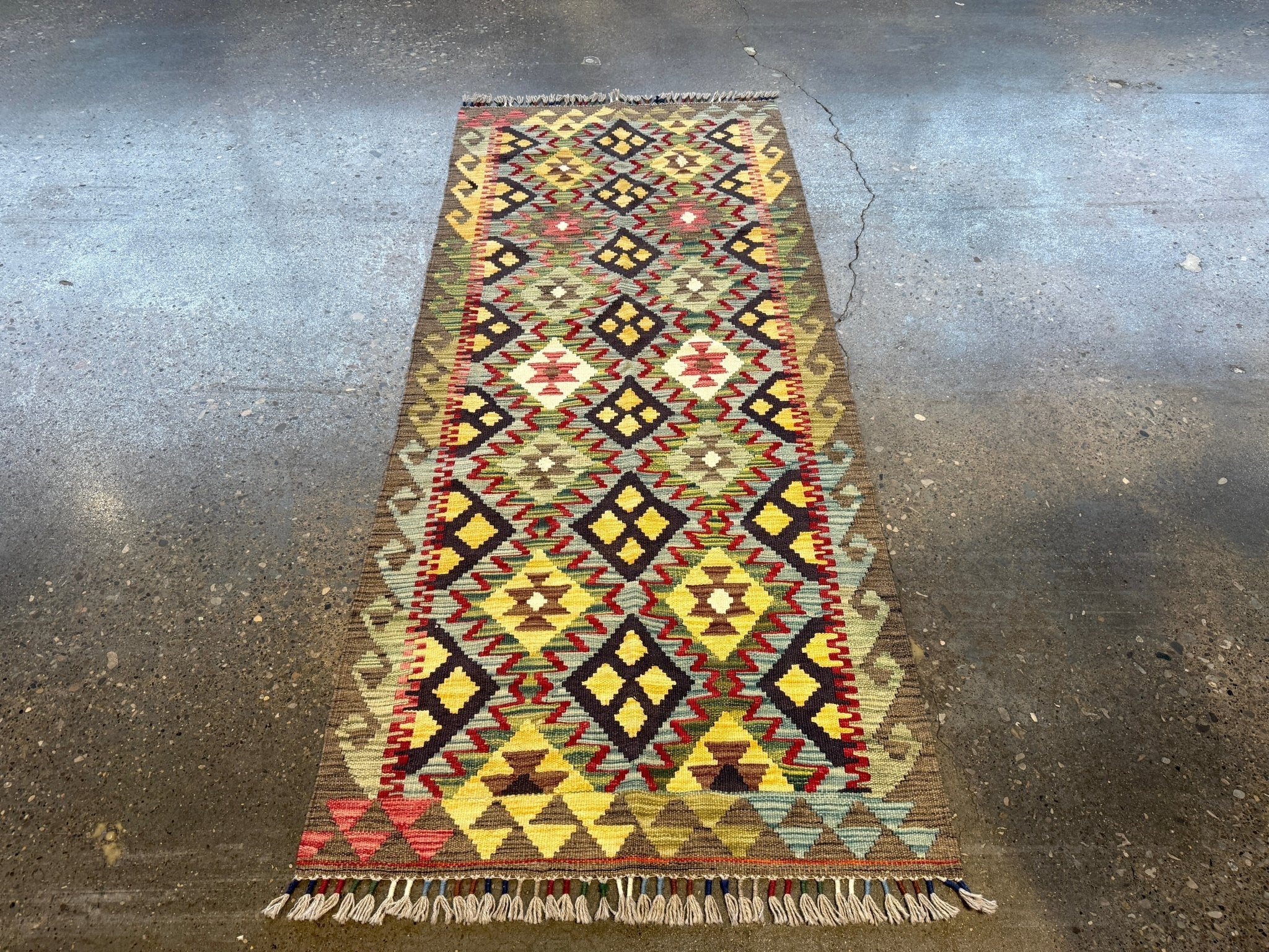 Small kilim rug with tall central diamond field in reds, yellows, and dark blue; fringed hem