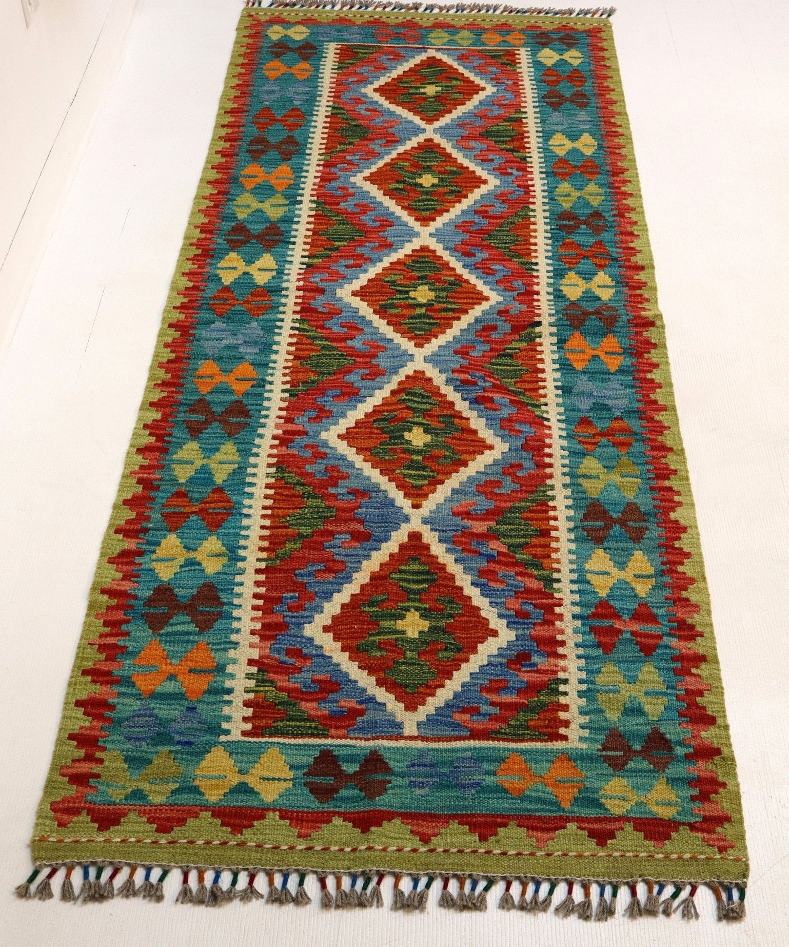 Afghan kilim rug with vertical diamond medallions, colorful borders, and short fringe