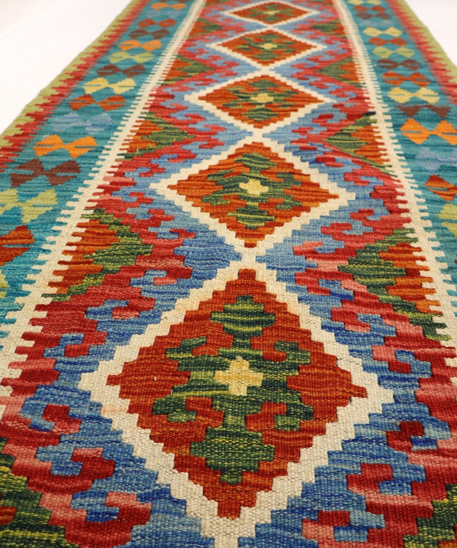 Afghan kilim rug with central diamond motifs, multicolor borders, and fringed trim