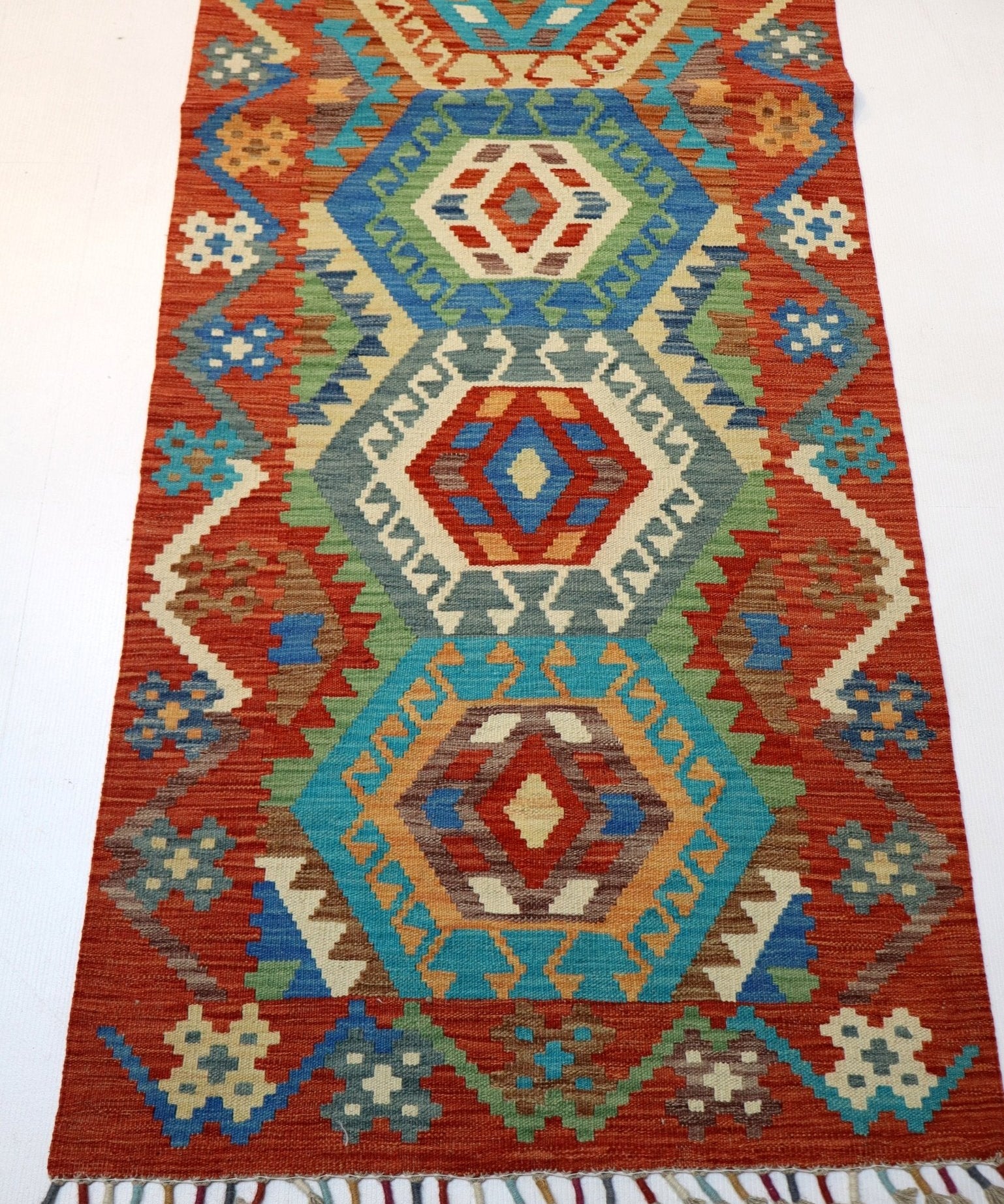 Afghan Kilim rug with rust, teal, blue and cream geometric medallions, fringed border