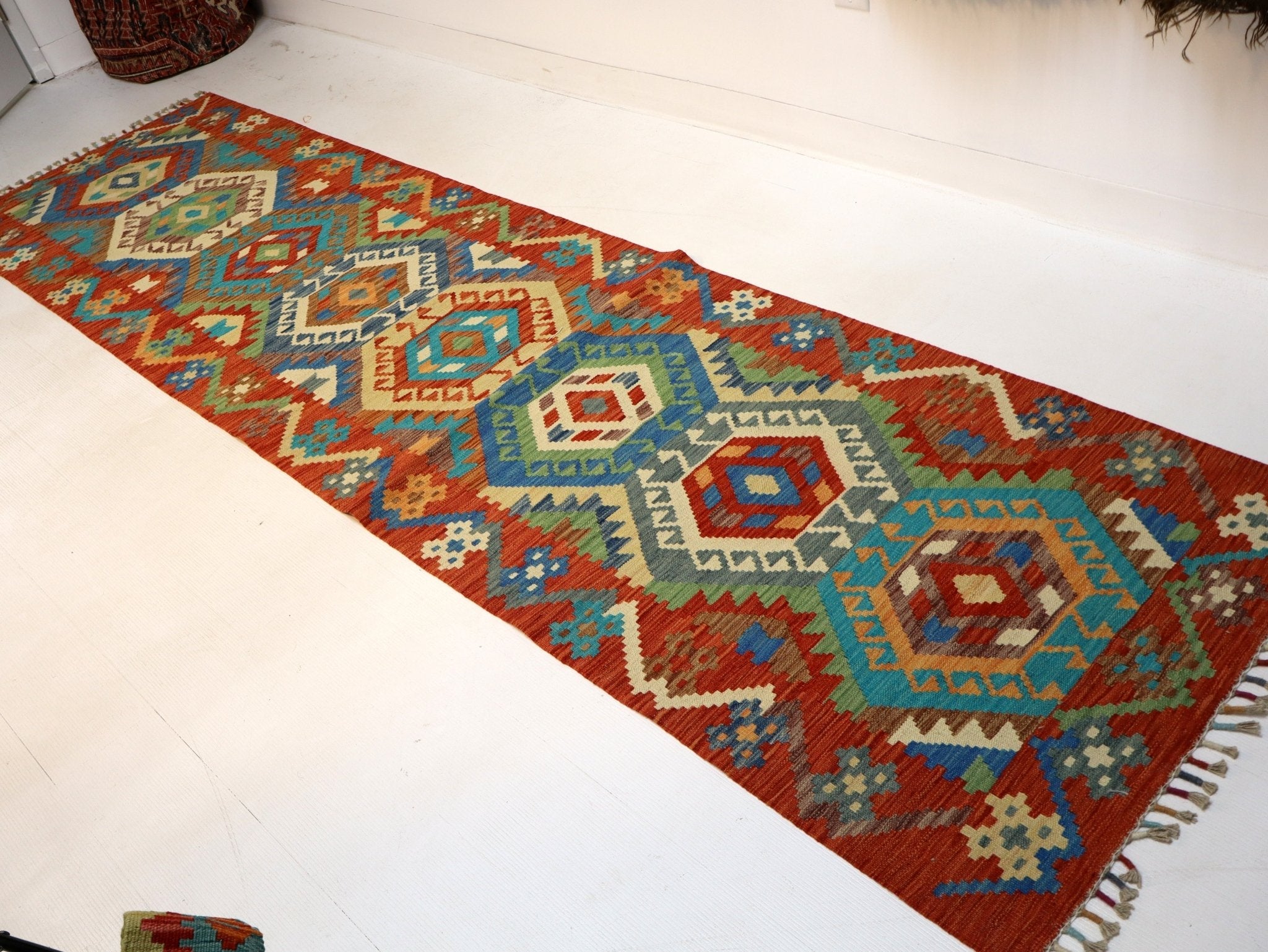 Rectangular kilim runner rug with layered geometric medallions and multicolor border.