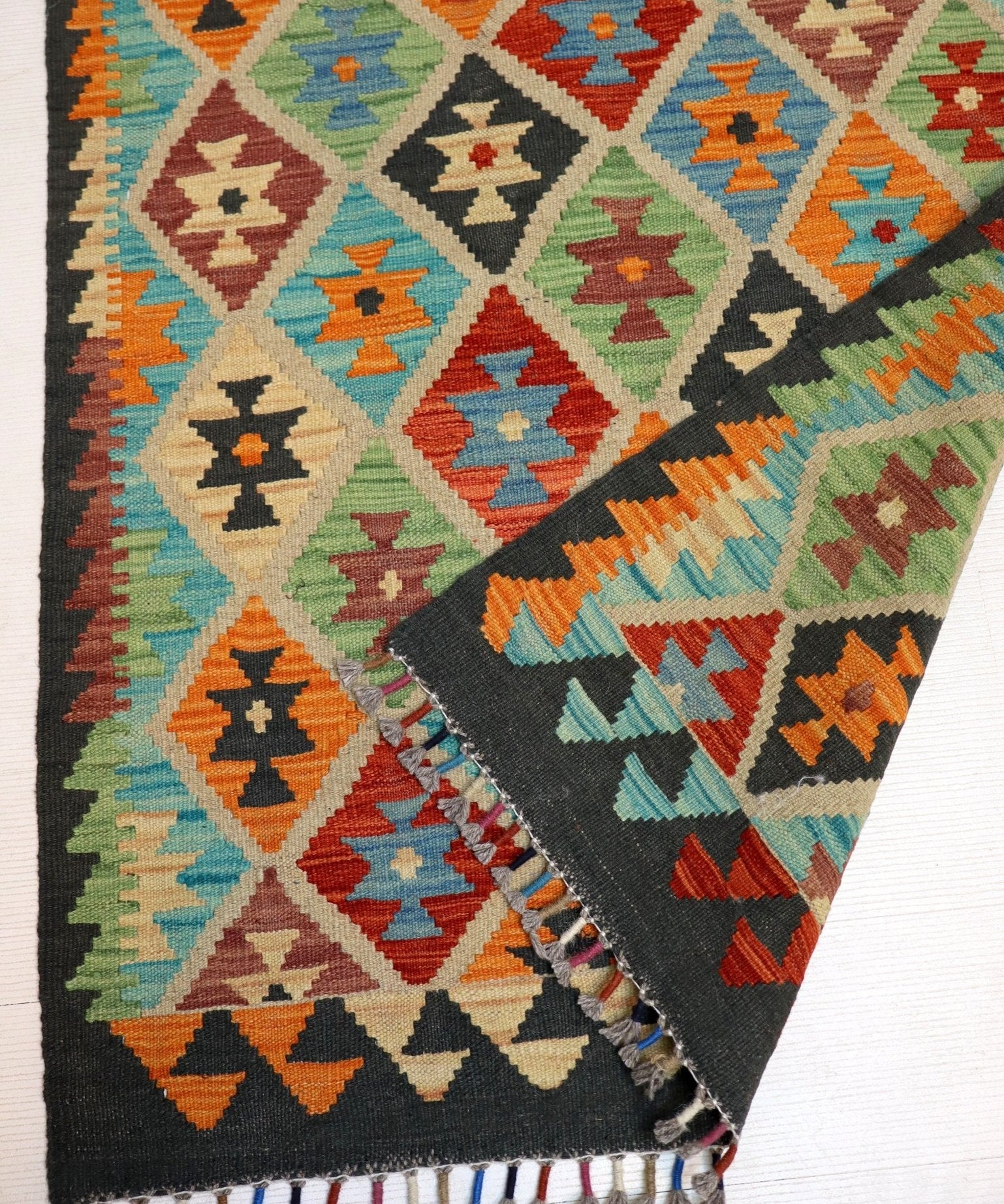 Colorful kilim rug with geometric diamond motifs and fringed border
