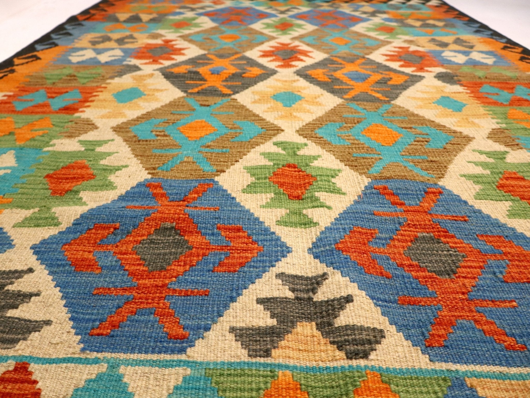 Close-up of kilim rug weaving with geometric motifs in blue, orange, teal, and green