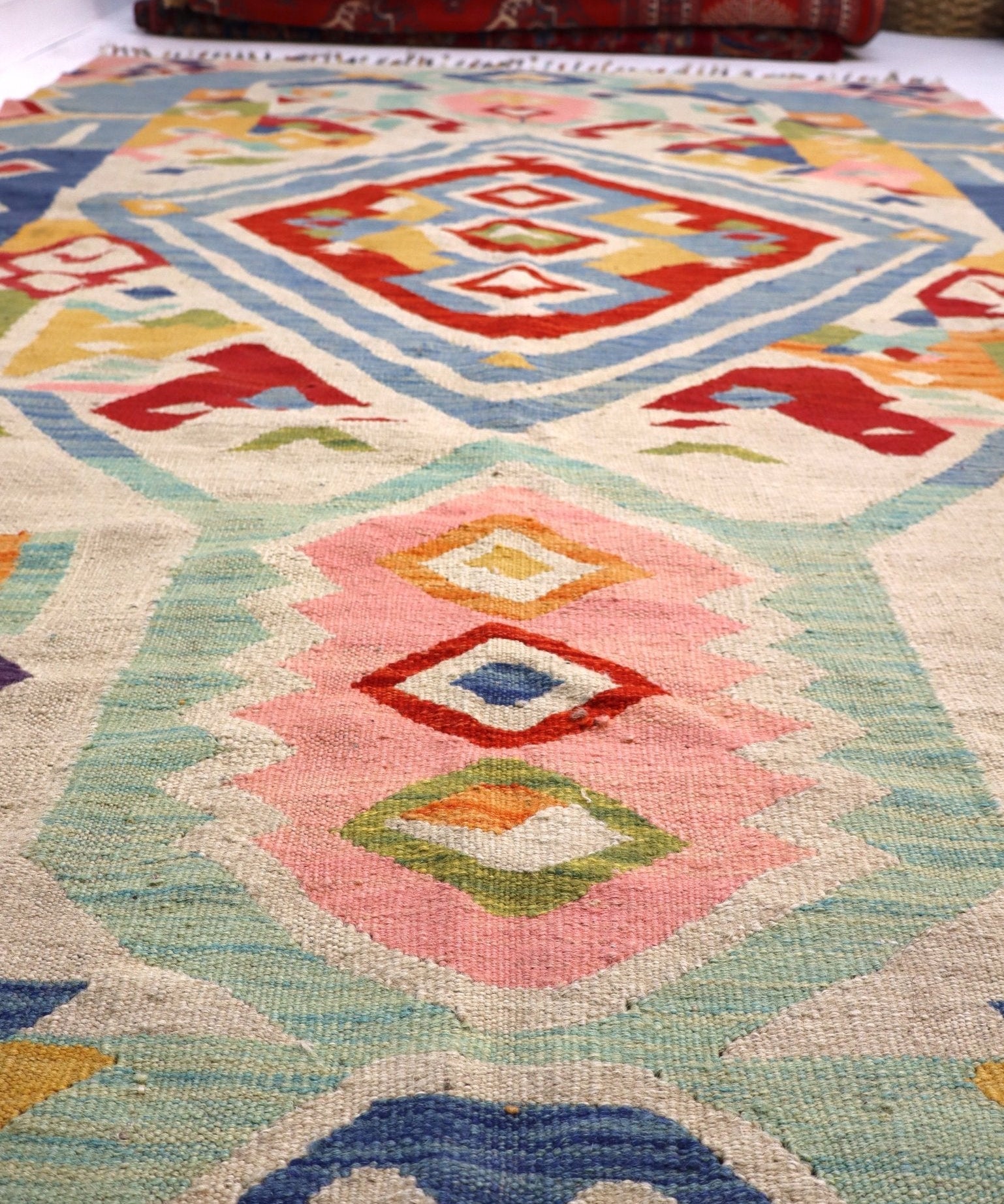 Close-up of kilim rug field with diamond medallions in blue, red, green, and beige