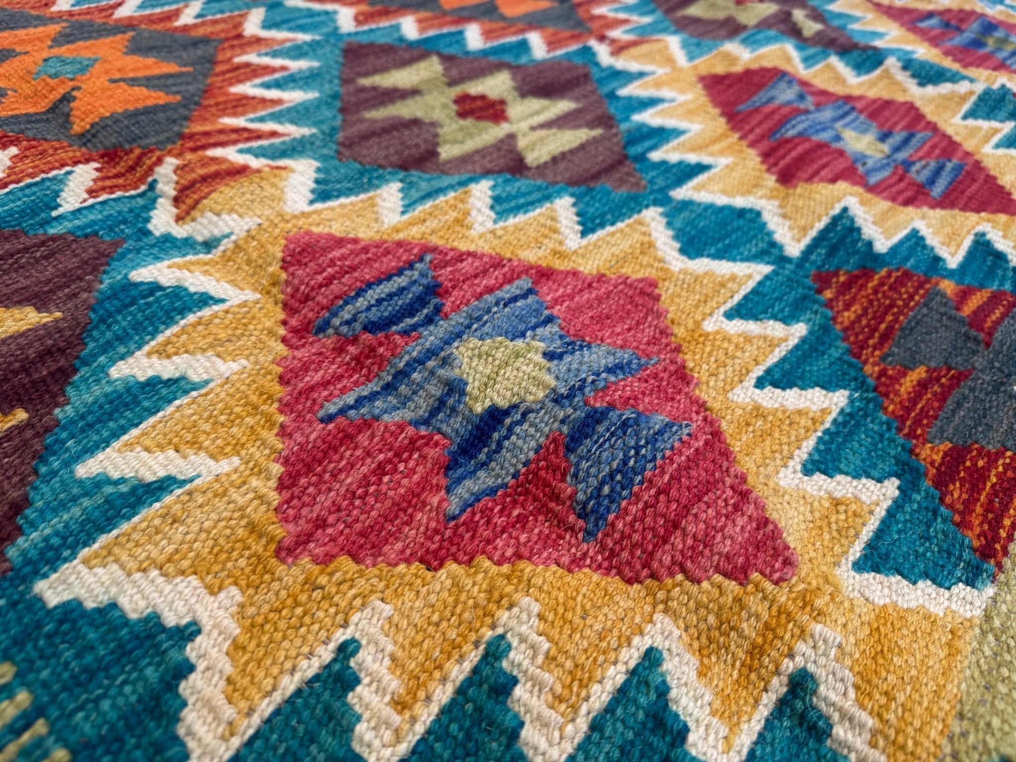 Kilim rug with multicolor geometric motifs and zigzag borders, tightly woven texture.