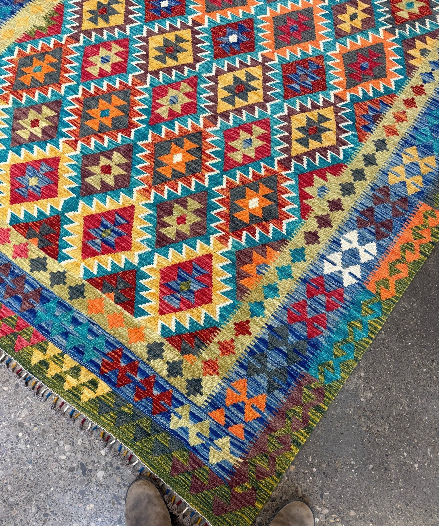 Multicolor geometric kilim rug with diamond motifs and short fringed border, corner view