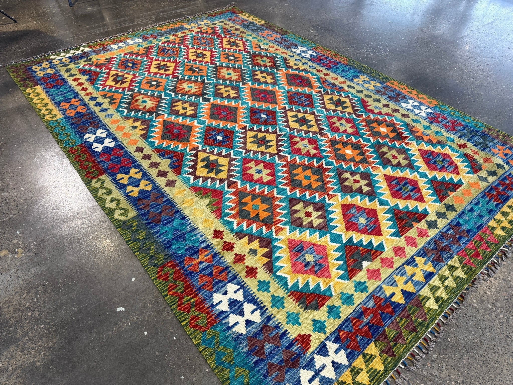 Flat kilim rug with vibrant geometric motifs, multicolor border, and visible fringes.