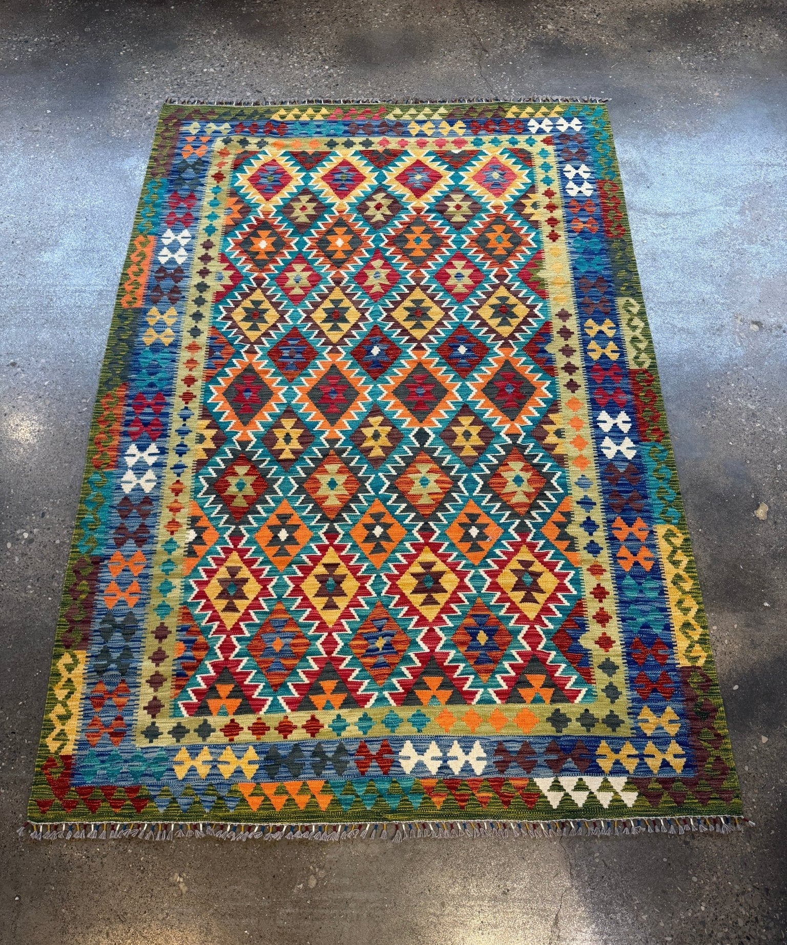 Multicolor geometric kilim rug with diamond pattern and fringe on all sides.