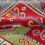 Folded edge and wool pile of red & green Kazak-inspired wool rug 24948.